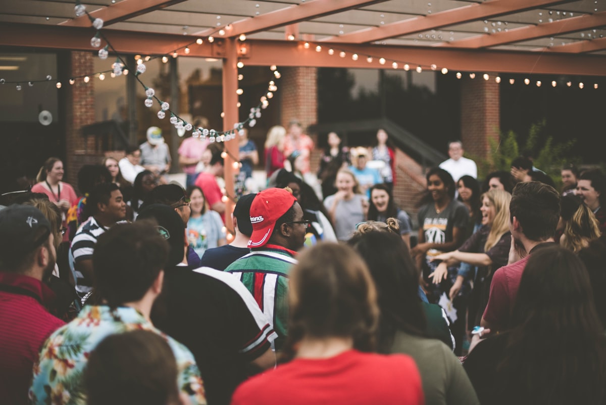 A crowd of friends laughing together at an outdoor evening gathering