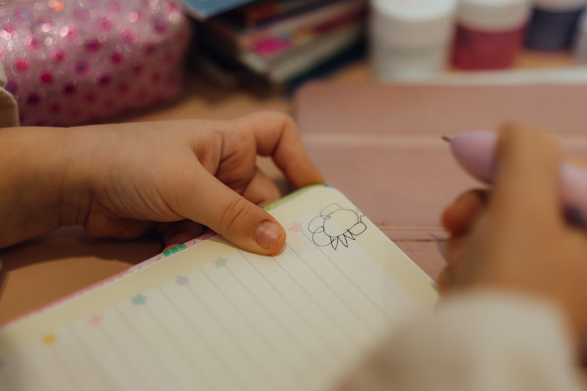 A hand sketching in a lined notebook, mid check-in